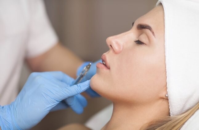 Young woman getting an injection by her eyebrow