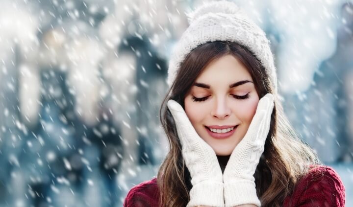 A beautiful young woman with perfect skin standing outside in the snow.